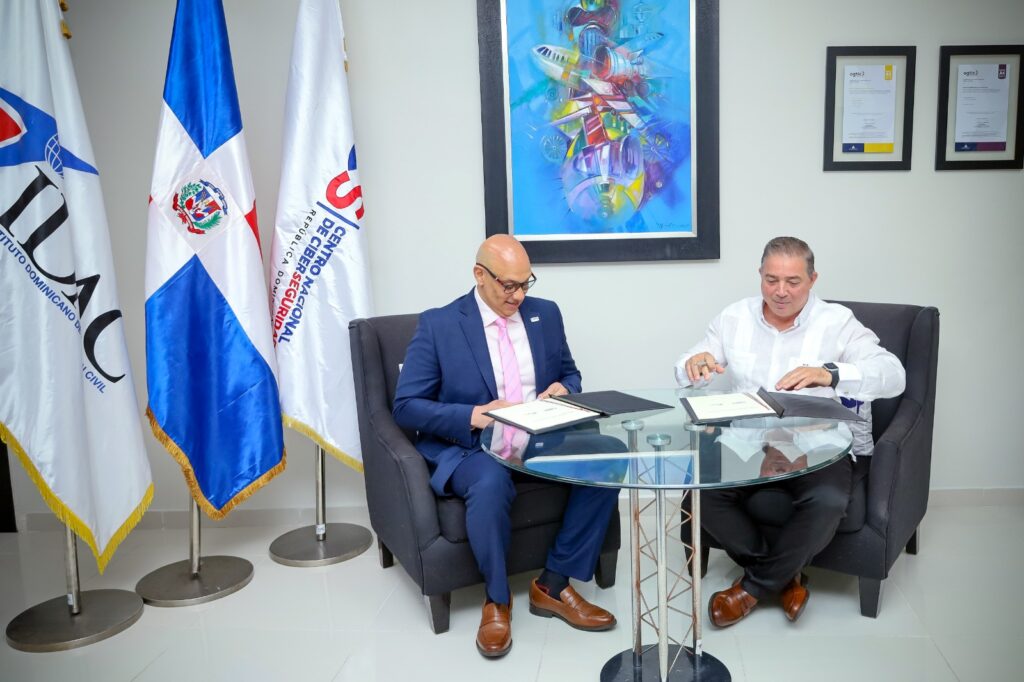 Héctor Porcella, director general interino del IDAC y el coronel Juan Gabriel Gautreaux, director ejecutivo del CNCS, firmando el acuerdo de cooperación